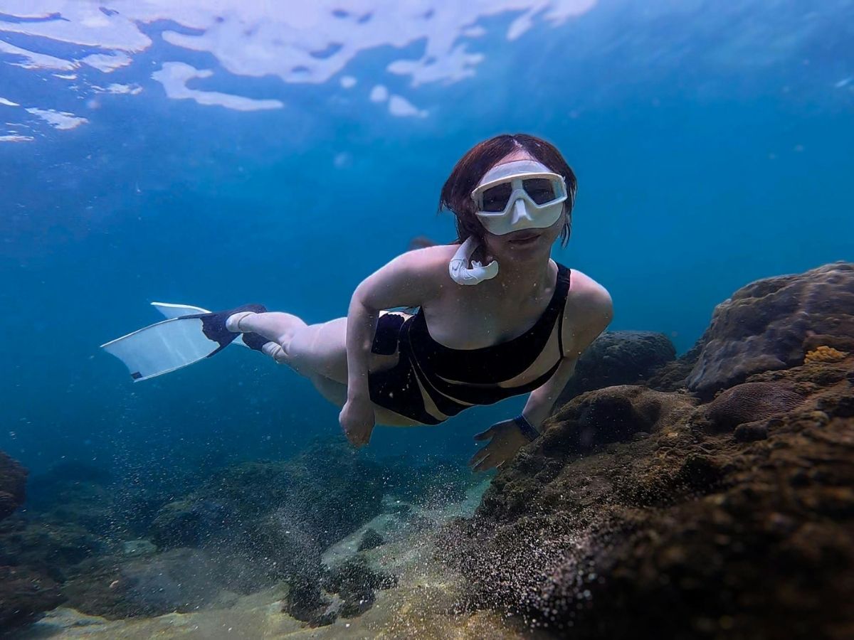 woman snorkeling underwater near coral reef in mini wall dive site