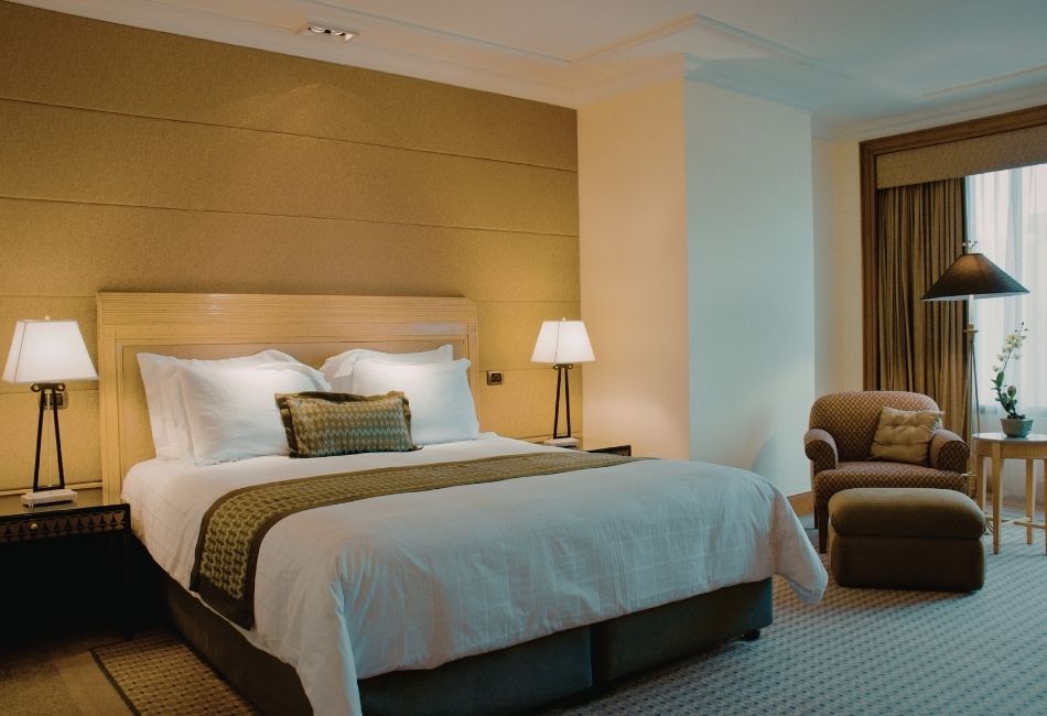 Elegant hotel room with queen bed, bedside lamps and armchair in Padma Resort Legian