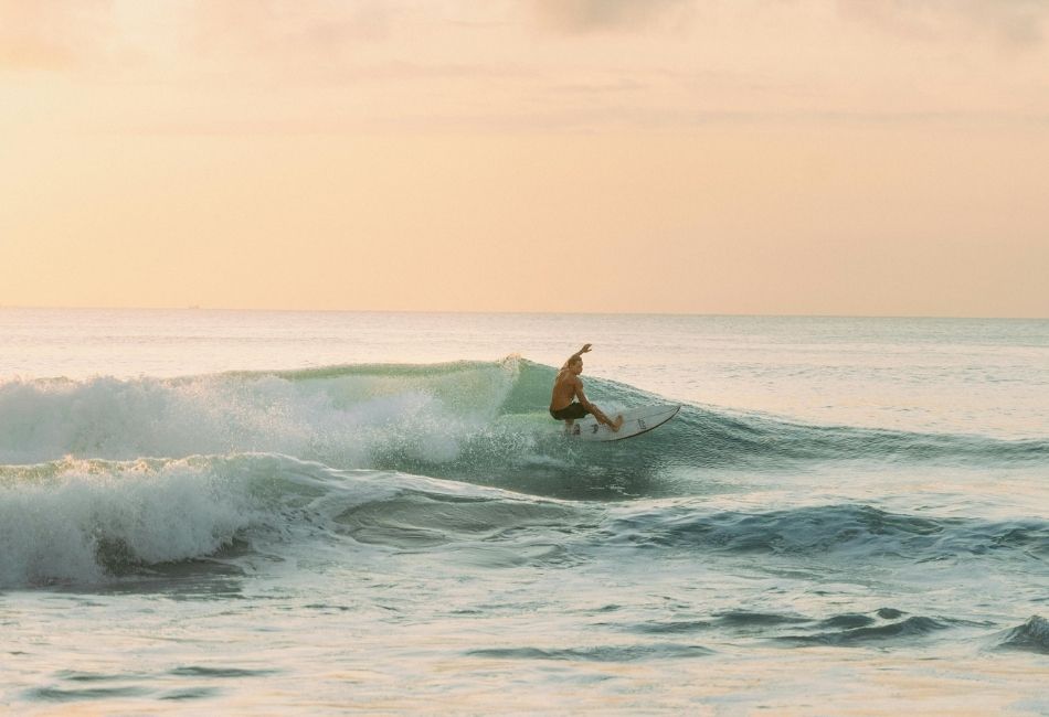 Surfer Riding Waves at Sunset on Keramas Beach in Bali